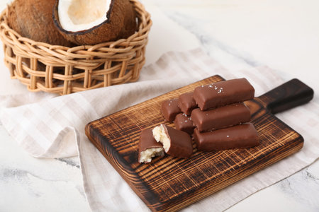 Wooden board with tasty chocolate covered coconut candies on white backgroundの写真素材