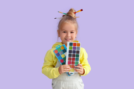 Cute little girl with paints on lilac background