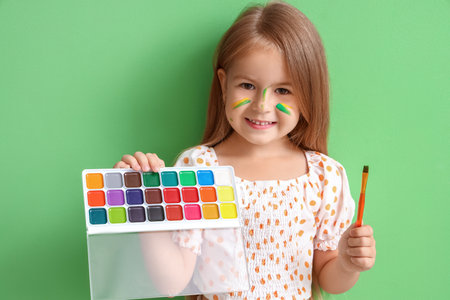 Cute little girl with paints on green backgroundの写真素材
