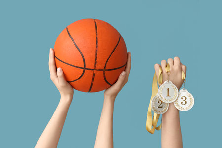 Female hands with basketball and medals on blue backgroundの写真素材