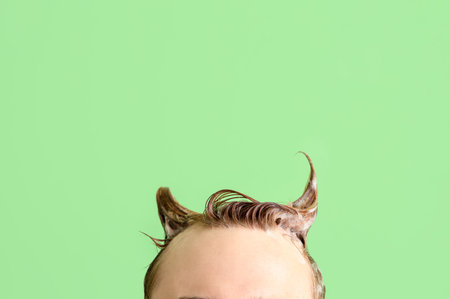 Young man with applied shampoo on his hair against green backgroundの写真素材