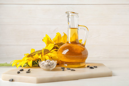 Decanter of sunflower oil and glass bowl with seeds on white wooden backgroundの写真素材