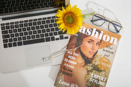Beautiful sunflower, magazine, eyeglasses, necklace and modern laptop on light backgroundの写真素材