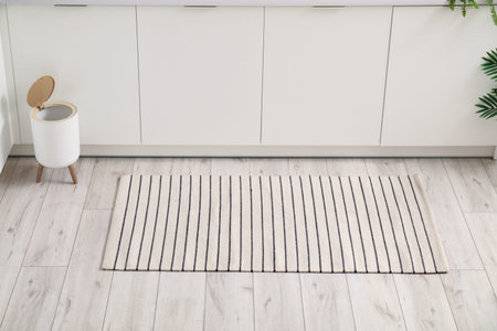 Stylish rug and trash bin on floor in kitchenの写真素材