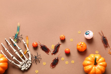 Halloween composition with candy bugs, pumpkins and skeleton hand on brown backgroundの写真素材