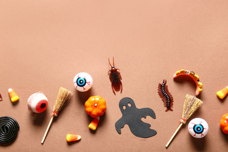 Halloween composition with candy bugs, eyeballs and brooms on brown backgroundの写真素材