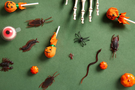 Halloween composition with candy bugs and pumpkins on green background