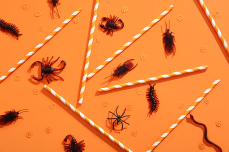 Halloween composition with candy bugs and straws on orange backgroundの写真素材