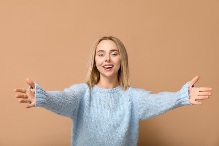 Young woman opening arms for hug on beige backgroundの写真素材