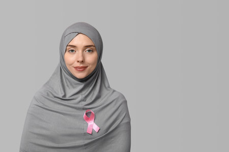 Muslim woman with pink ribbon on gray background. Breast cancer awareness conceptの写真素材