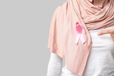 Muslim woman with pink ribbon on gray background, closeup. Breast cancer awareness conceptの写真素材
