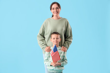 Little boy with USA flag and his mother on blue background. Veterans Day celebrationの写真素材
