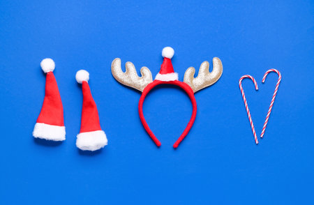 Cute Christmas reindeer horns with Santa hats and candy canes on blue backgroundの写真素材