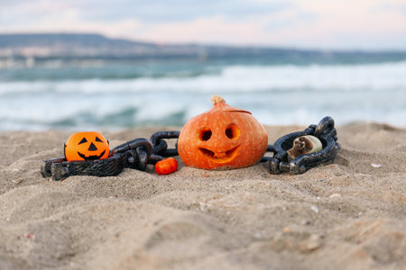 Carved pumpkin for Halloween with chain and basket on beachの写真素材