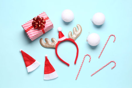 Cute reindeer horns with Santa hats, Christmas balls, gift box and candy canes on blue background