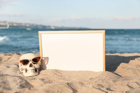 Skull for Halloween with chalkboard and stylish sunglasses on beachの写真素材