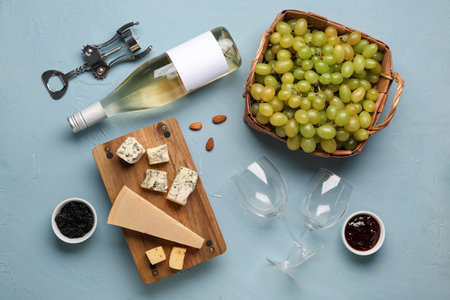Glasses and bottle of wine with grapes, cheese, jam, black caviar, corkscrew and nuts on blue backgroundの写真素材