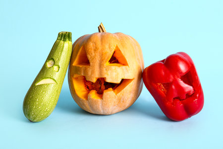Carved pumpkin, zucchini and bell pepper for Halloween on blue backgroundの写真素材