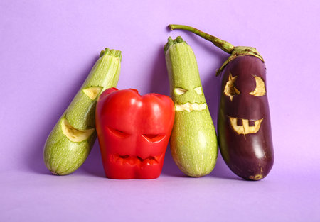 Carved zucchini, bell pepper and eggplant for Halloween on lilac backgroundの写真素材