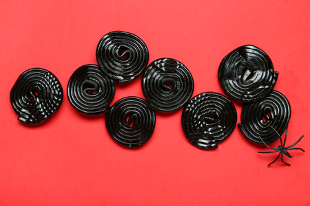 Halloween composition with licorice candies and spider on red backgroundの写真素材