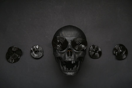 Halloween composition with skull and licorice candies on black backgroundの写真素材