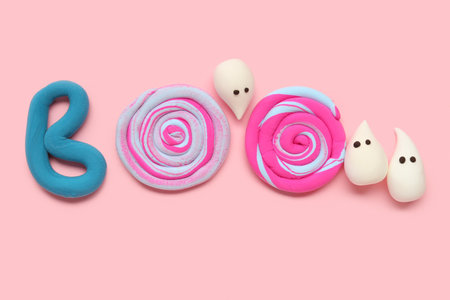 Halloween composition with word BOO made from licorice candies and ghosts on pink backgroundの写真素材