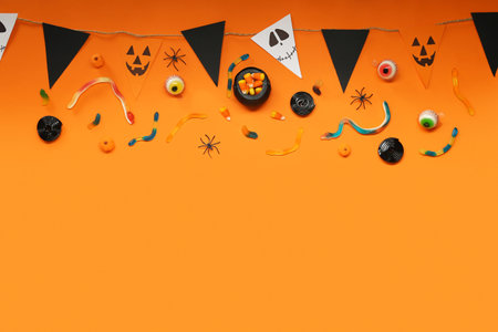 Halloween composition with sweet candies and garland on orange backgroundの写真素材