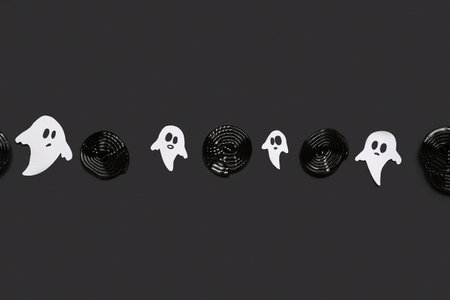 Halloween composition with licorice and ghosts on black background