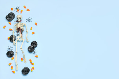 Halloween composition with skeleton, sweet candies and spiders on blue backgroundの写真素材