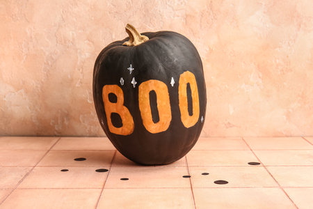 Painted Halloween pumpkin with word BOO on beige tiled tableの写真素材