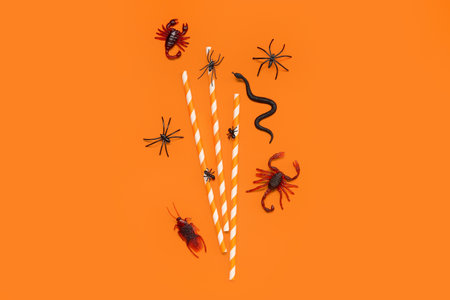 Halloween composition with candy bugs and straws on orange backgroundの写真素材