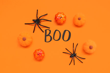 Halloween composition with pumpkins, spiders and word BOO on orange backgroundの写真素材
