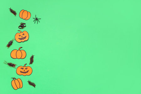 Halloween composition with pumpkins and candy bugs on green backgroundの写真素材