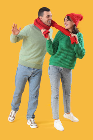 Beautiful young couple in warm clothes on yellow backgroundの写真素材