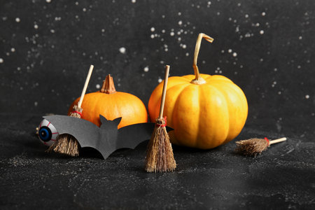 Halloween composition with brooms, pumpkins and bat on black grunge backgroundの写真素材