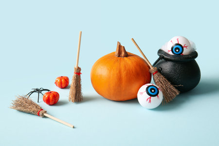 Halloween composition with pumpkins, brooms, eyeballs and cauldron on blue backgroundの写真素材