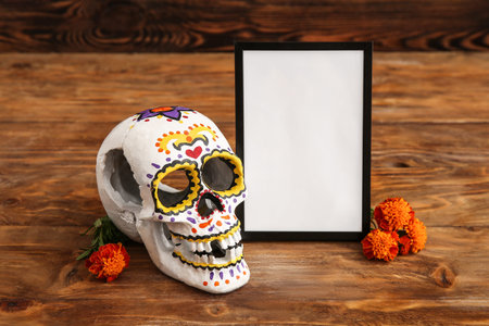 Marigold flowers with painted skull and frame on brown wooden background. Celebration of Mexico's...