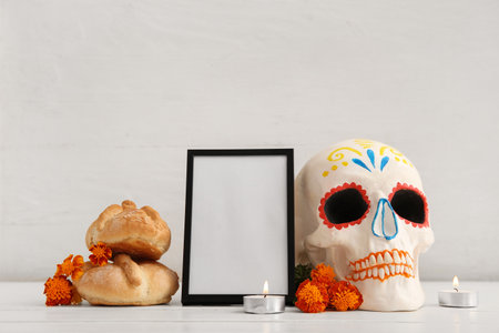 Bread of the dead with flowers, candles, frame and painted skull on white wooden table. Celebration of Mexico's Day of the Dead (El Dia de Muertos)の写真素材