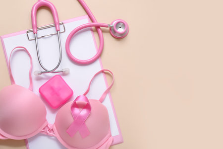 Bra with awareness ribbon, pill box, stethoscope and clipboard on beige background. Breast cancer conceptの写真素材