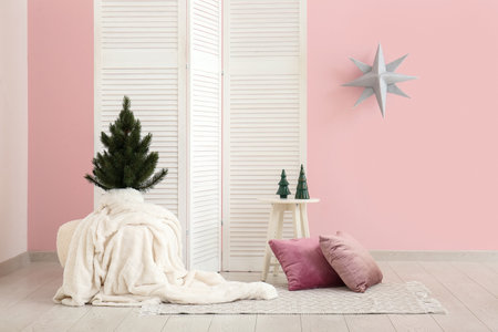 Interior of festive room with Christmas tree and decor near pink wallの写真素材