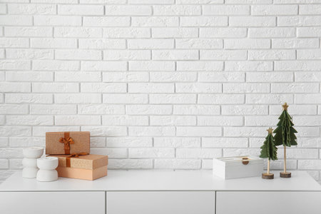 Cabinet with gift boxes and Christmas decor near white brick wallの写真素材