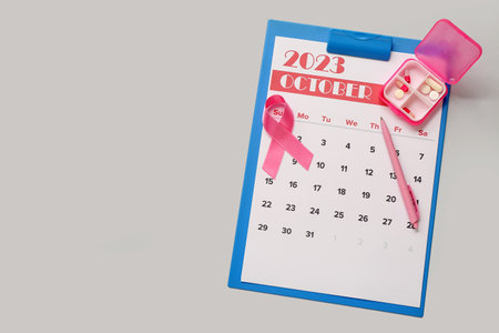 Pink ribbon with pill box and calendar on gray background. Breast cancer awareness conceptの写真素材