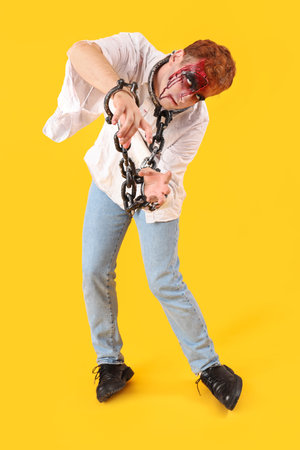 Scary zombie man with chains on yellow backgroundの写真素材