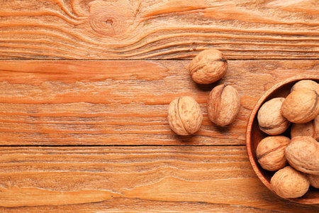 Bowl with walnuts on wooden background
