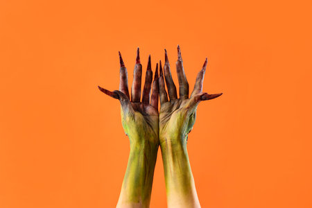 Hands of witch with claws on orange background. Halloween celebrationの写真素材