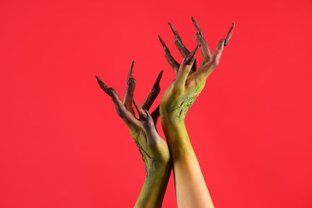 Hands of witch with claws on red background. Halloween celebrationの写真素材