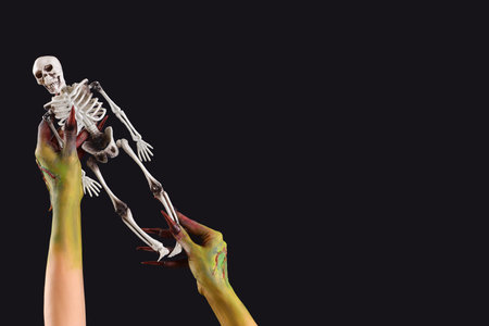 Witch with toy skeleton on black background. Halloween celebrationの写真素材