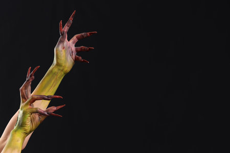Hands of witch with claws on black background. Halloween celebrationの写真素材