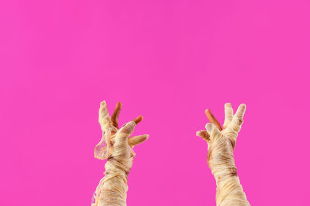 Mummy hands on pink background. Halloween celebration