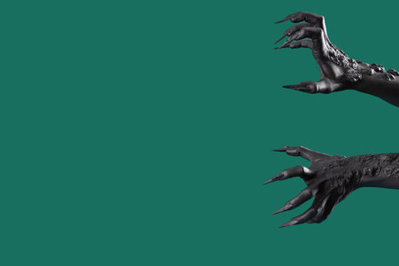 Black hands of witch with claws on green background. Halloween celebrationの写真素材
